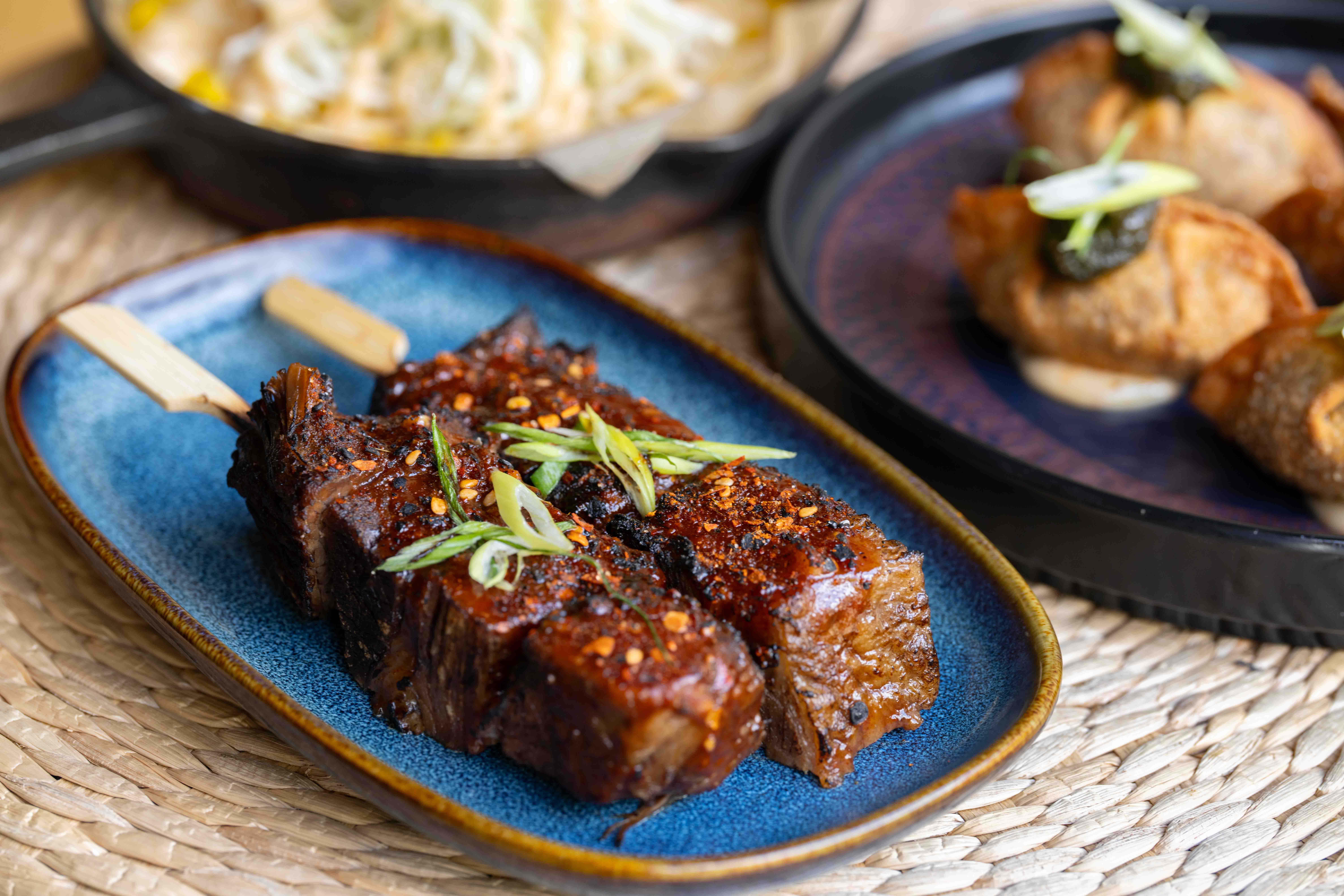Glazed beef skewer served on a blue plate at Shobu